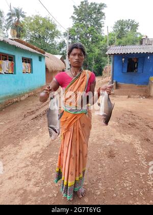 BHUBANESWAR, INDE - 25 juin 2021 : femme tribale de l'État d'Odisha en Inde avec de gros poissons carpes en main Banque D'Images