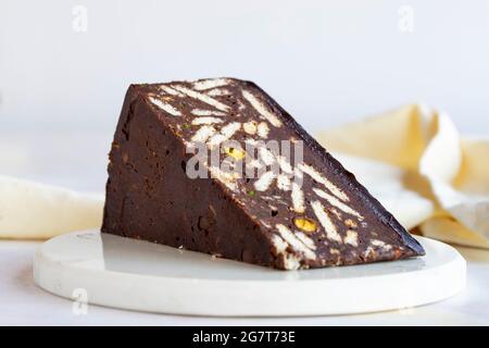 Gâteau en mosaïque avec pistache et chocolat sur fond de bois blanc. Gâteau de mosaïque Banque D'Images