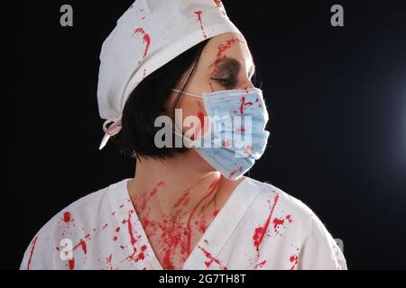 femme sanglante sombre médecin sur fond noir regardant de côté vue de profil, monochrome Banque D'Images