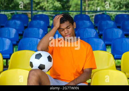 Brésilien avec un ballon de football assis sur une tribune de football vide Banque D'Images