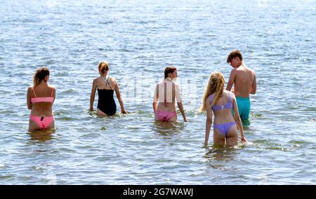 Dundee, Tayside, Écosse, Royaume-Uni. 16 juillet 2021. Météo au Royaume-Uni : temps chaud et ensoleillé qui traverse le nord-est de l'Écosse avec une température maximale de 29 °C. Les amateurs de plage prennent la journée en profitant du soleil d'été le long de la plage de Broughty Ferry à Dundee. Cinq jeunes jouent dans l'eau avant d'aller nager dans la rivière Tay. Crédit : Dundee Photographics/Alamy Live News Banque D'Images