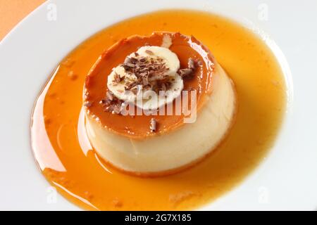 Une crème caramel décorée de tranches de banane et de copeaux de chocolat. Banque D'Images