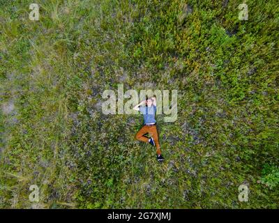 Vue aérienne d'un drone d'un homme allongé sur son dos dans une grande herbe Banque D'Images