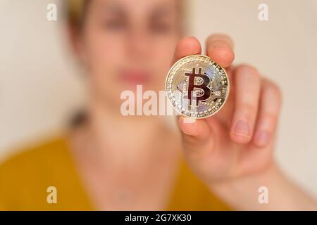 Vue rapprochée d'une femme tenant une pièce de monnaie crypto-monnaie Bitcoin dans sa main Banque D'Images