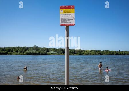 Londres, Royaume-Uni. 16 juillet 2021. Météo au Royaume-Uni – les personnes qui nagent dans l'eau à Ruislip Lido, dans le nord-ouest de Londres, lorsque la température a atteint 25 °C. Les prévisions sont pour des conditions plus chaudes au cours du week-end, qui devraient atteindre 30 °C. Un panneau avertit les gens de ne pas entrer dans l'eau car aucun sauveteur n'est en service et les dangers dans l'eau incluent les excréments de la sauvagine, un parasite vivant dans les escargots d'eau douce et le verre brisé, mais les gens continuent à aller dans le lac. Credit: Stephen Chung / Alamy Live News Banque D'Images