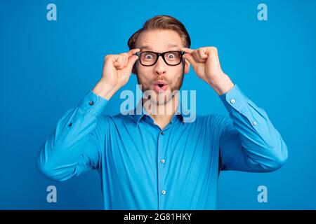 Photo du jeune homme excité heureux sourire positif stupéfié nouvelles surpris isolé sur fond bleu de couleur Banque D'Images