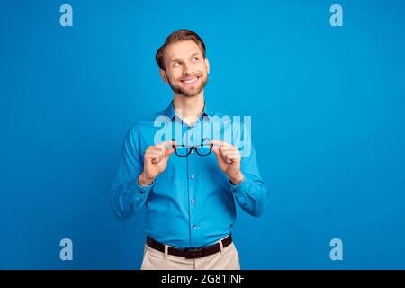 Photo de jeune homme beau heureux positif sourire rêve look vide espace isolé sur fond bleu de couleur Banque D'Images