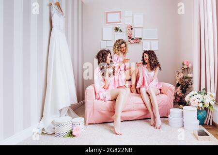 Les copines boivent du champagne rose avant la cérémonie de mariage en pyjama. Banque D'Images