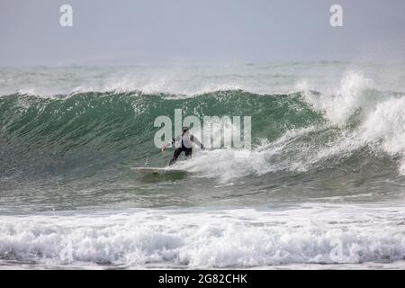 Australien en combinaison sur sa planche de surf surfant sur les vagues à une plage de Sydney par un jour hivernaux, Sydney, NSW, Australie Banque D'Images