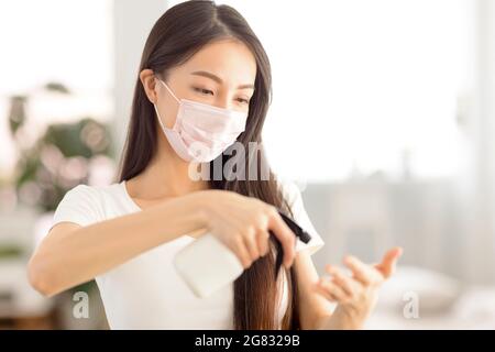 Jeune femme portant un masque médical et utilisant un spray de désinfection Banque D'Images