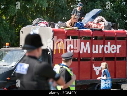 Scunthorpe, Royaume-Uni. 16 juillet 2021. Les policiers regardent les manifestants pour rébellion animale assis au-dessus d'un camion fixé orné de McMurder pendant la manifestation. Plus de 50 manifestants de la rébellion animale ont fermé la seule usine de distribution de hamburgers de McDonald's, l'usine OSI Food Solutions au Royaume-Uni, en blockant l'entrée avec des balises en bambou et des véhicules. Les rebelles exigent que McDonald's passe à des menus entièrement basés sur des plantes d'ici 2025 et mette fin à la souffrance de milliards de vies et pour éviter la crise climatique tout en sauvant la forêt amazonienne. Crédit : SOPA Images Limited/Alamy Live News Banque D'Images