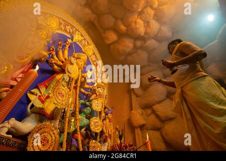 Kolkata, Inde - 16 octobre 2018 : jeune prêtre hindou adorant la déesse Durga avec la coquille de la comque sous la fumée sainte, rituel du festival Durga Puja. - prise de vue Banque D'Images