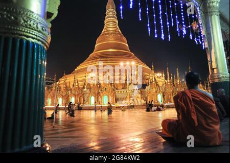 21.01.2014, Yangon, Myanmar, Asie - les moines bouddhistes sont assis devant la stupa illuminée de la pagode dorée du Shwedagon dans la soirée. Banque D'Images