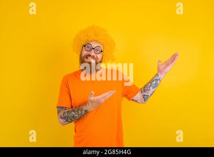 Homme heureux avec barbe, perruque jaune et lunettes Banque D'Images