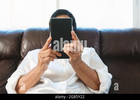 Senior woman using mobile phone while sitting on sofa at home Banque D'Images