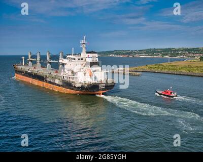 Le transporteur de vrac Cabrera quitte le port de Belfast en juin 2021 lors d'une soirée claire et ensoleillée en juin 2021. Le navire est escorté par le bateau à remorqueurs Masterman. Banque D'Images