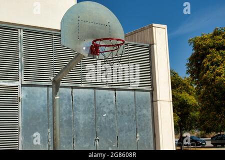 panier de basket-ball en métal sur la piste de rue entourée de bâtiments Banque D'Images