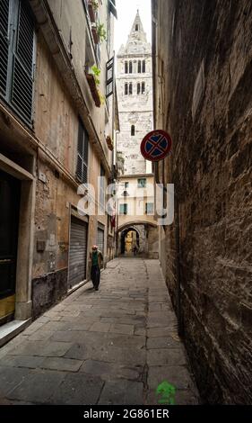 Une ruelle étroite 'carugio' dans le centre historique de Gênes, en Italie, avec un vieil homme et le clocher de l'église de la basilique Santa Maria delle Vigne Banque D'Images