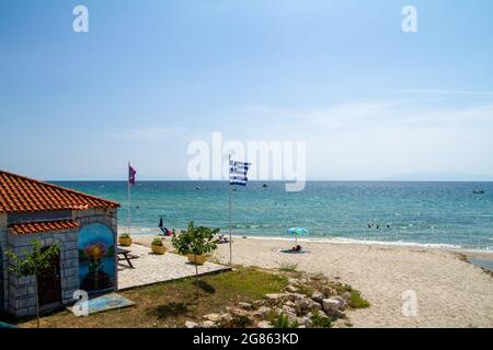 Siviri, Grèce, 10 juillet 2021. Grèce, vue sur la plage de Siviri avec un drapeau grec. Ancien port de pêche de Kassandria, aujourd'hui une belle petite vill touristique Banque D'Images