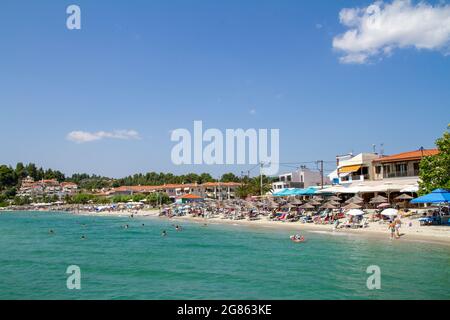 Siviri, Grèce, 10 juillet 2021. Grèce, vue sur la plage de Siviri avec un drapeau grec. Ancien port de pêche de Kassandria, aujourd'hui une belle petite vill touristique Banque D'Images