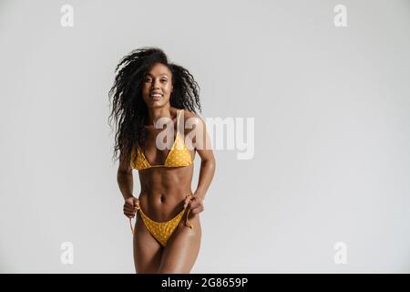 Femme noire en maillot de bain souriant et regardant l'appareil photo isolé sur fond blanc Banque D'Images