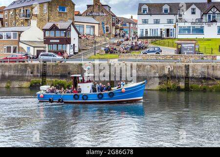 Un bateau touristique retourne des îles Farne voisines au port Seahouses de Northumberland, qui abrite également une petite flotte de pêche. Banque D'Images