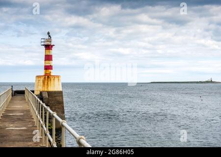 Phare à l'entrée de la baie de Ramble Harbour au bout de la jetée sud de Ramble, Northumberland, Angleterre, Royaume-Uni Banque D'Images