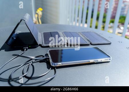 Charge d'un smartphone depuis la maison avec un chargeur portable pour panneau solaire.consommation et charge avec de petits panneaux solaires i Banque D'Images