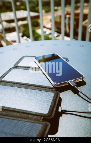 Charger un smartphone depuis la maison avec un chargeur portable pour panneau solaire. Banque D'Images