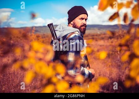 Saison de chasse en automne. Chasseur avec fusil de chasse. Recherche automatique. Poacher avec Rifle trating certains Deers. Gros plan Portrait d'un chasseur de hamdsome. Banque D'Images