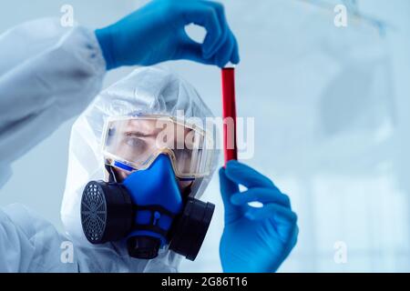le chercheur regarde le liquide rouge dans la bouteille. Banque D'Images