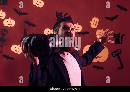 Homme face effrayant avec l'horreur maquillage tenant la tête de citrouille lanterne jack sur fond de ciel. Assistant, sorcier, verrou de sécurité. Halloween homme avec le sourire à l'obscurité Banque D'Images