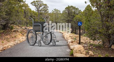 Panneau d'accès pour fauteuils roulants et personnes handicapées sur un chemin, fond vert du parc. Matériel médical pour handicapés pour profiter de la nature. Accessible public recrée Banque D'Images