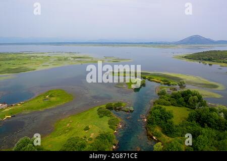 Vue aérienne époustouflante par drone sur l'immense étendue parsemée d'îles du parc national du lac Skadar sous un ciel bleu clair dans le pittoresque Monténégro. Banque D'Images