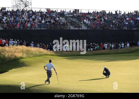 Le Collin Morikawa des États-Unis se pataise sur le 16e vert tandis que Louis Oosthuizen, d'Afrique du Sud, observe pendant la troisième journée de l'Open au Royal St George's Golf Club à Sandwich, dans le Kent. Date de la photo: Samedi 17 juillet 2021. Banque D'Images