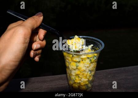 Délicieux fromage Sweetcorn, beurre frais, plat de style rue servi dans une tasse transparente. La plupart du temps mangé chaud et cheesey pendant la saison des pluies en plein air Banque D'Images