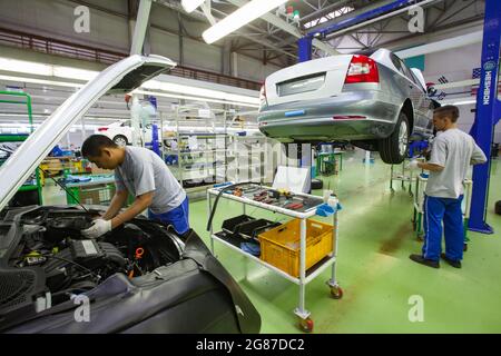 Ust'-Kamenogorsk,Kazakhstan,mai 31,2012: Usine de construction automobile de la société Asia-Auto. ASSEMBLAGE DE voitures KIA. L'ouvrier (gauche) installe les pièces du moteur. Banque D'Images