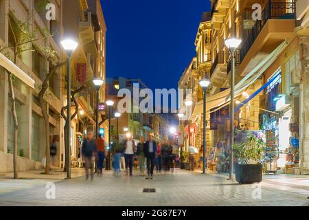 Héraklion, Crète, Grèce - 26 avril 2018 : rue du 25 août dans la ville d'Héraklion la nuit avec des personnes à pied. Les gens sont flous en mouvement Banque D'Images