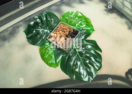 nourriture biologique saine dans un bol sur les feuilles tropicales, différents fruits secs amandes dattes secs raisins secs noirs d'or (kishmish) régime de jim Banque D'Images