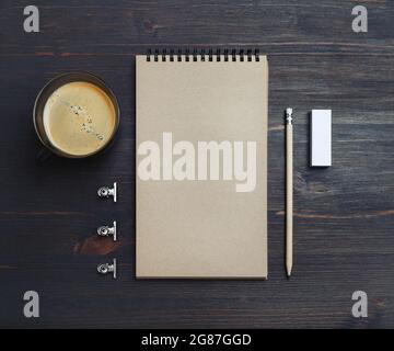 Photo d'un carnet de croquis kraft vierge, d'un crayon, d'une gomme et d'une tasse à café sur fond de table en bois.vue du dessus. Pose à plat. Banque D'Images