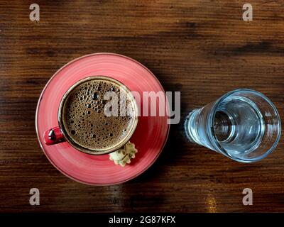 Tasse traditionnelle de café turc rouge, petit verre d'eau sur une table en bois. Banque D'Images