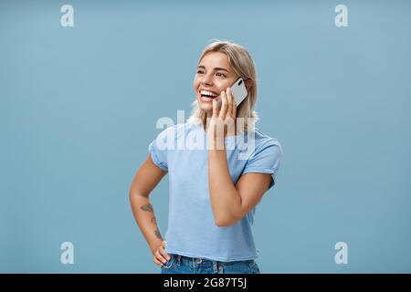 Photo à la taille de sociable amusé et heureux attrayant caucasien à poil long femme dans un t-shirt décontracté debout à moitié tourné regardant à gauche avec la main sur la hanche Banque D'Images