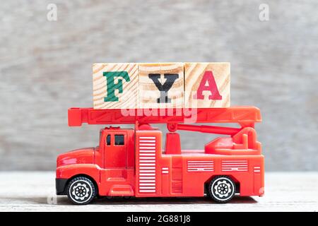 Rouge camion d'incendie tenir le bloc de lettres dans le mot FYA (abréviation de pour votre action ou attention) sur fond de bois Banque D'Images