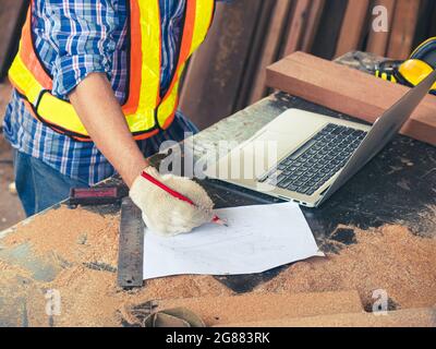 Le menuisier prend des commandes pour la production de meubles avec les clients via système de télécommunication sur ordinateurs portables dans une usine de bois. Fabricant Banque D'Images