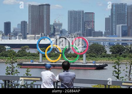 Tokio, Japon. 18 juillet 2021. Deux personnes se tiennent sur une baie devant les grands anneaux olympiques. Les anneaux se trouvent sur un radeau dans la baie de Tokyo, en face du quartier d'Odaiba. Les Jeux olympiques de Tokyo de 2020 auront lieu du 23 juillet 2021 au 8 août 2021. Credit: Michael Kappeller/dpa/Alay Live News Banque D'Images