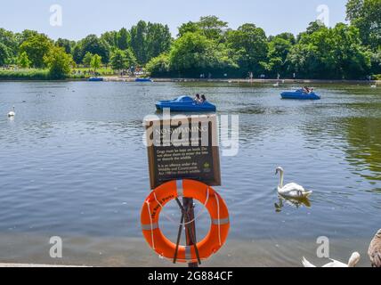 Londres, Royaume-Uni. 17 juillet 2021. Un panneau pas de natation, des gens dans des bateaux à pédales et un cygne vu sur le lac de Serpentine à Hyde Park le jour le plus chaud du Royaume-Uni de l'année jusqu'à présent. Crédit : SOPA Images Limited/Alamy Live News Banque D'Images