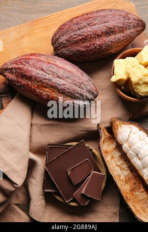 Fruits frais de cacao, beurre et chocolat sur fond de bois Banque D'Images