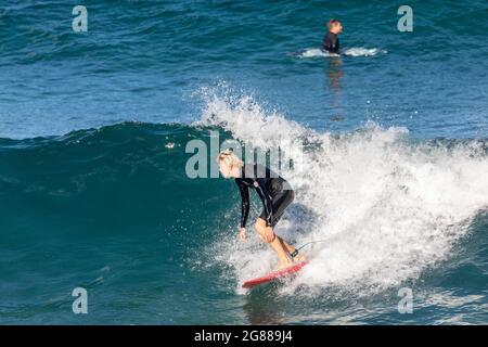 Australien en combinaison sur sa planche de surf surfant sur les vagues à une plage de Sydney par un jour hivernaux, Sydney, NSW, Australie Banque D'Images