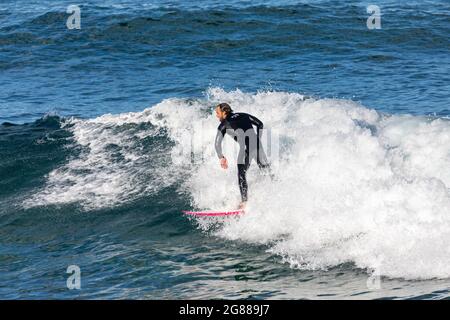 Australien en combinaison surfant sur les vagues à bord de mer à Avalon Beach Sydney, un jour hiverne, Australie Banque D'Images