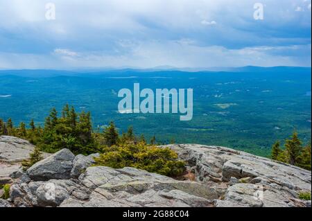 Vue de l'ouest depuis le mont Sommet de Kearsarge vers le lac Sunapee et le mont. Ascutney. Affleurement granitique rocheux et épinettes raboutées. Pics et crêtes éloignés Banque D'Images